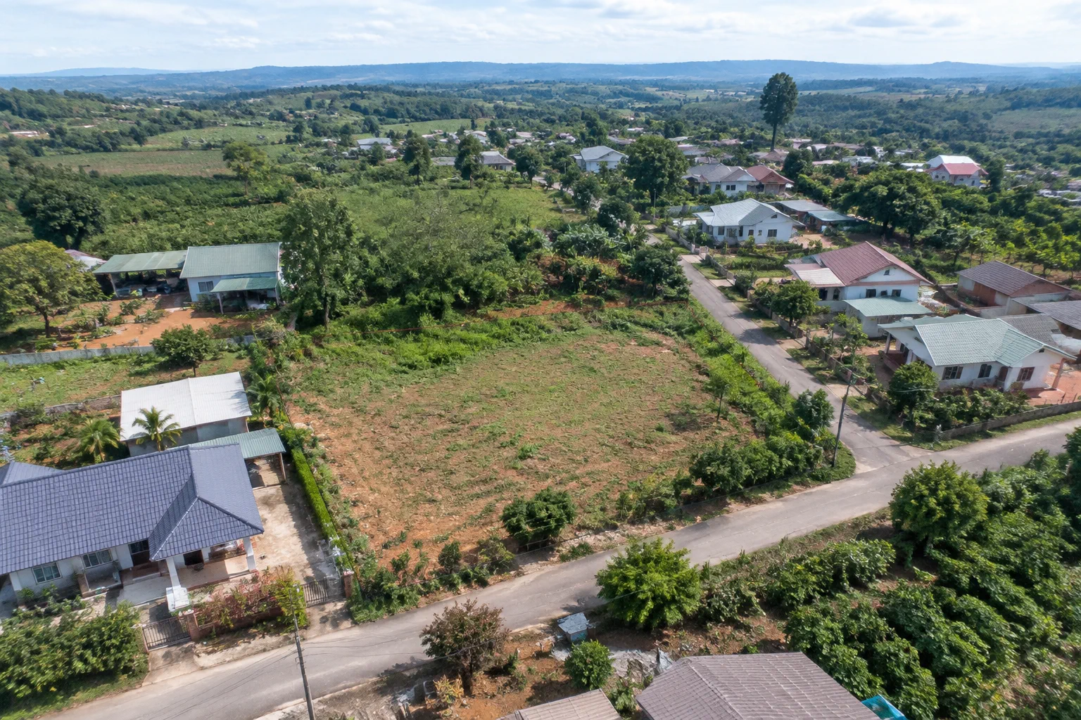 Toàn cảnh khu dân cư xen kẽ khu đất trống tại Đắk Nông nhìn từ góc cao, thể hiện mối liên hệ giữa khu đất, đường giao thông, nhà ở xung quanh và các tiện ích hiện hữu để người mua